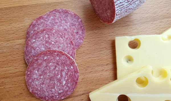 Cheese and salami on wooden table — Stock Photo, Image