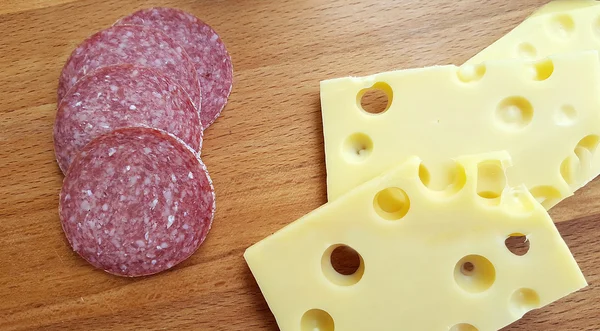 Cheese and salami on wooden table — Stock Photo, Image