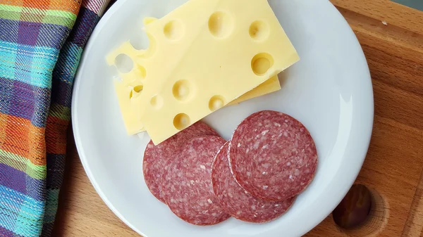 Сыр и салями на белой тарелке — стоковое фото