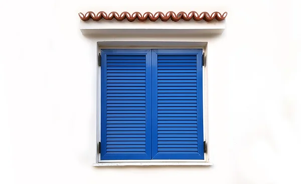 Fönster med stängda blå fönsterluckor på vit vägg — Stockfoto