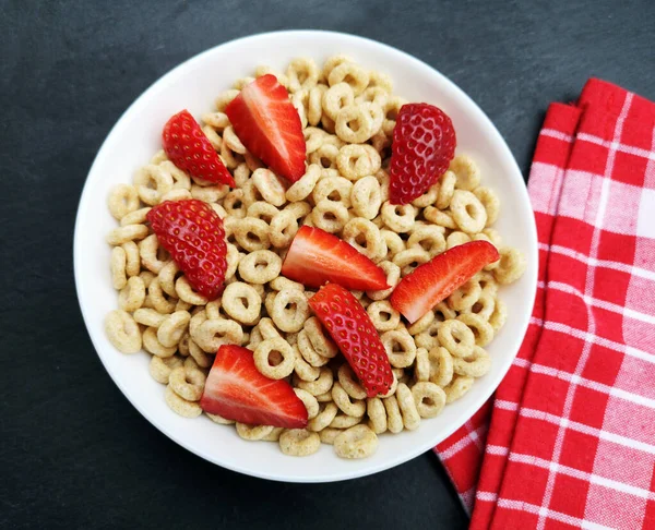 Whole grain cereal rings in a bowl and strawberries on a table. Healthy breakfast