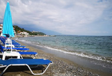 Platamonas, Pieria, Yunanistan 'da deniz kenarındaki çakıl taşı plajında boş plaj sandalyeleri