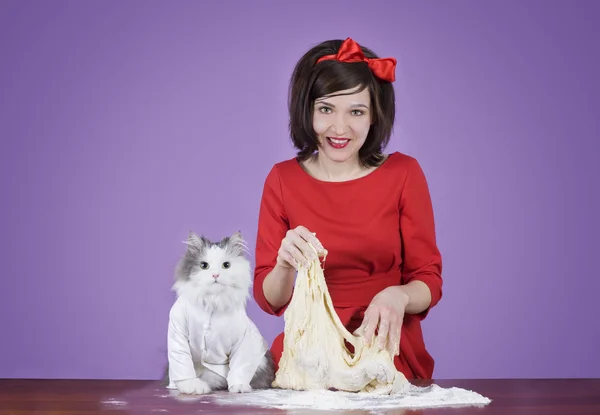 Молодая женщина и пушистый кот готовят тесто — стоковое фото