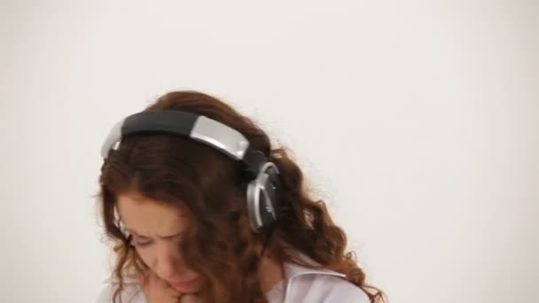 Kvinna i hörlurar och vit skjorta lyssnar på musik och dans — Stockvideo