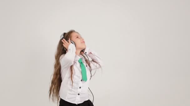 Kleines süßes Mädchen, das mit Kopfhörern Musik hört und tanzt — Stockvideo