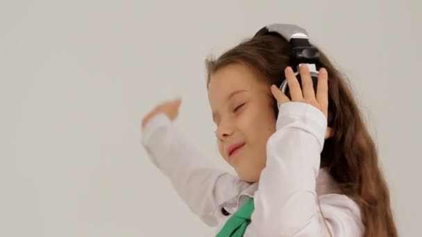 Retrato de una niña pequeña con auriculares escuchando música y bailando. Movimiento lento — Vídeos de Stock