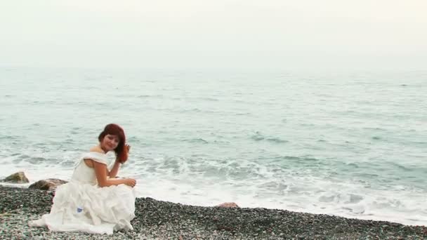 Mujer bonita sentada en la playa de guijarros en el Mar Negro — Vídeos de Stock