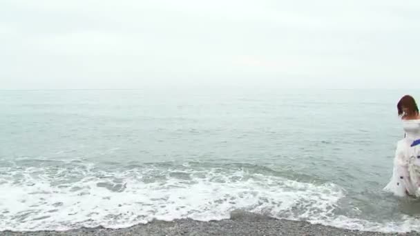 Mooie vrouw In witte jurk wandelen langs de kust — Stockvideo