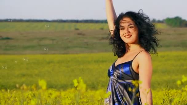Lycklig kvinna blåser bubblor i ett fält av Raps. — Stockvideo
