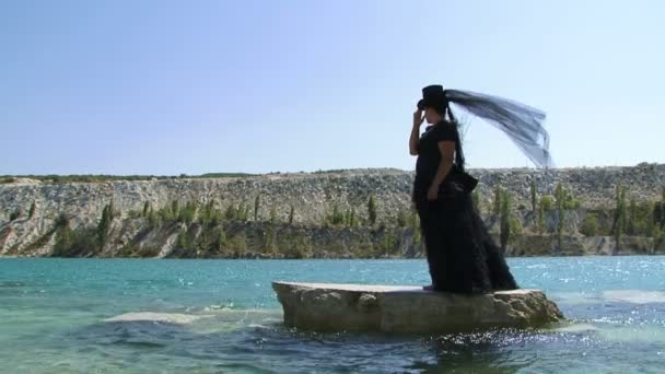站在悬崖上池塘上的黑衣女人 — 图库视频影像