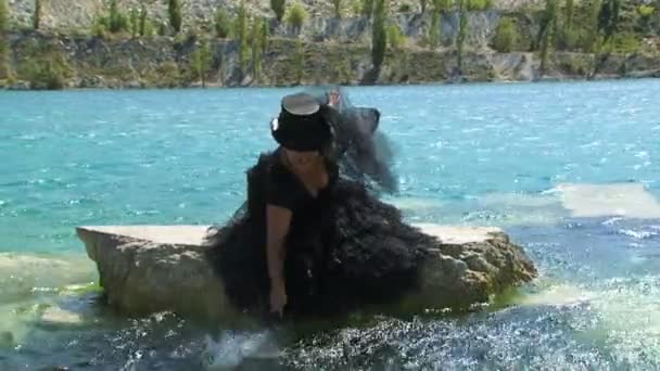 Mujer en negro salpicaduras de agua en el lago — Vídeo de stock