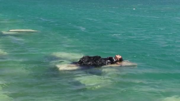 Mulher em preto deitado no penhasco no lago — Vídeo de Stock