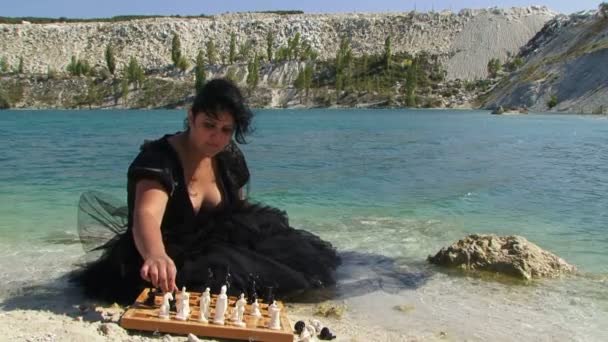 Portrait of Young Woman In Black Dress Playing Chess Near Lake — Stock Video