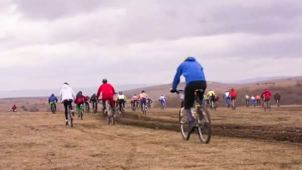 EDITORIAL. Grupo de jovens ciclistas movendo-se em campo no dia maçante — Vídeo de Stock