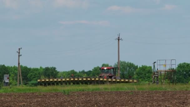 Сельскохозяйственный трактор с сеялкой начинает сеять урожай в поле — стоковое видео
