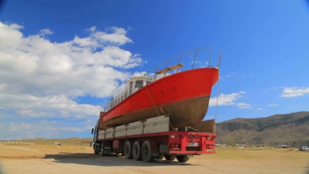 Leitartikel. Großer LKW mit Segelboot an Bord setzt sich an Land in Bewegung — Stockvideo