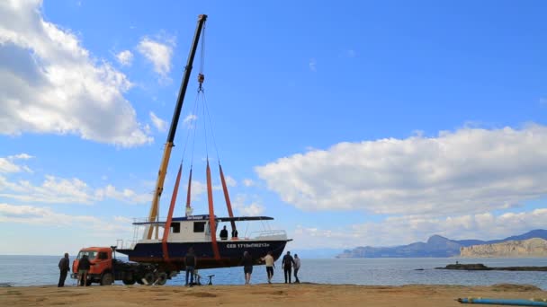 EDITORIALE. Lavoratori che sollevano l'incrociatore di festa a Seashore con la gru-macchina — Video Stock