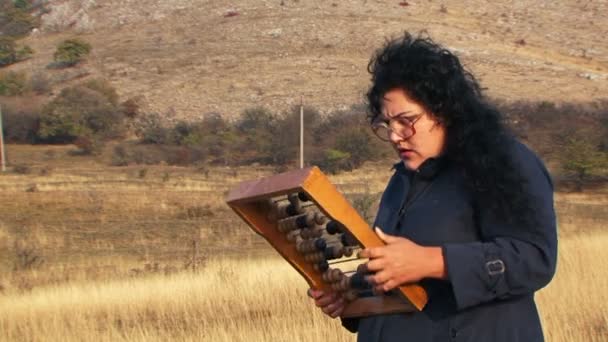 Mujer extraña en negro jugando y mirando a través de cuentas de estar en la naturaleza — Vídeos de Stock