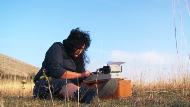 Lustige Frau tippt auf historischer Schreibmaschine, die in der Natur auf dem Boden sitzt — Stockvideo