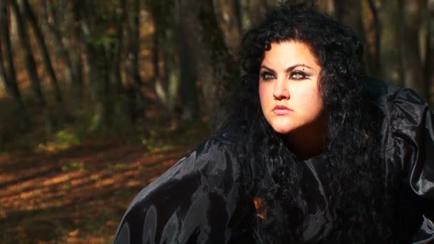 Femme aux cheveux foncés dans le noir regardant dans la distance dans la forêt d'automne — Video