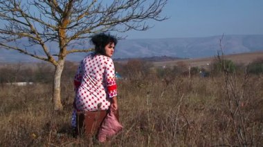 Young Woman In White Dotted Dress Sitting On Suitcase At Nature