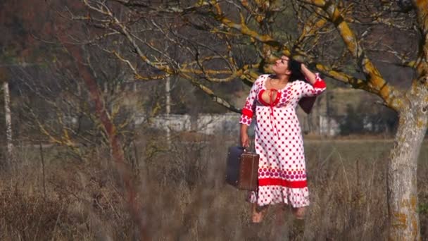 Giovane donna in bianco punteggiato vestito a piedi a prato — Video Stock