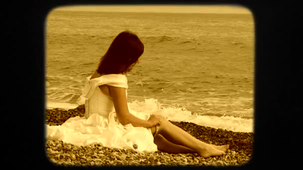 Όμορφη γυναίκα κάθεται στην παραλία και βάζοντας σε κάλτσες — Αρχείο Βίντεο