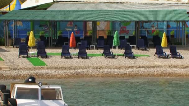 Chaise Longue negro de pie en la playa de guijarros — Vídeos de Stock