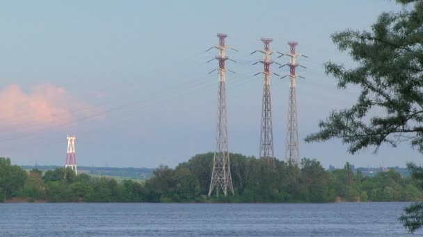 Висока напруга електропередачі електричних полюсів біля річки — стокове відео