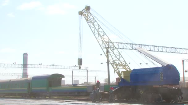 Spoorwegarbeiders laden wagon met grote kraan op station — Stockvideo