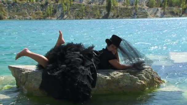 Woman In Black liggend op Rock op Lake — Stockvideo