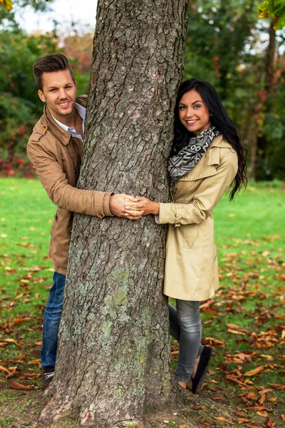 Pareja enamorada detrás de un árbol — Foto de Stock