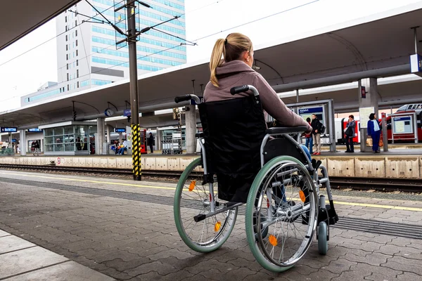 Woman sitting in a wheelchair at a train station — Stock Photo, Image