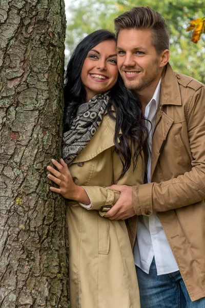 Enamoured couple behind a tree — Stock Photo, Image