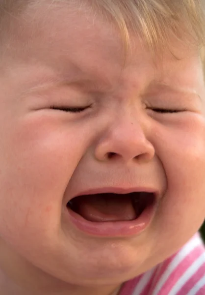 Bebê deitado em um gramado e chorando — Fotografia de Stock