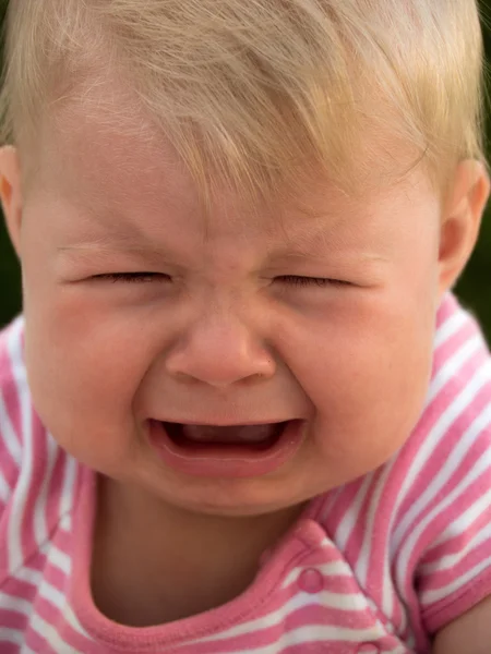 Baby lying on a lawn and crying — Stock Photo, Image