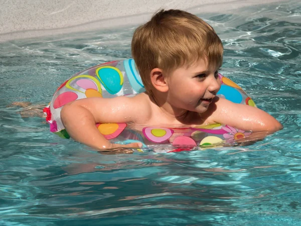 Ребенок с плавающим кольцом охлаждается в бассейне в жаркий день в — стоковое фото