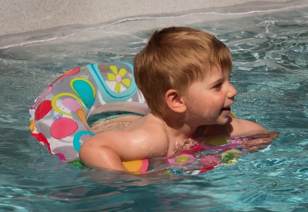 Ребенок с плавающим кольцом охлаждается в бассейне в жаркий день в — стоковое фото