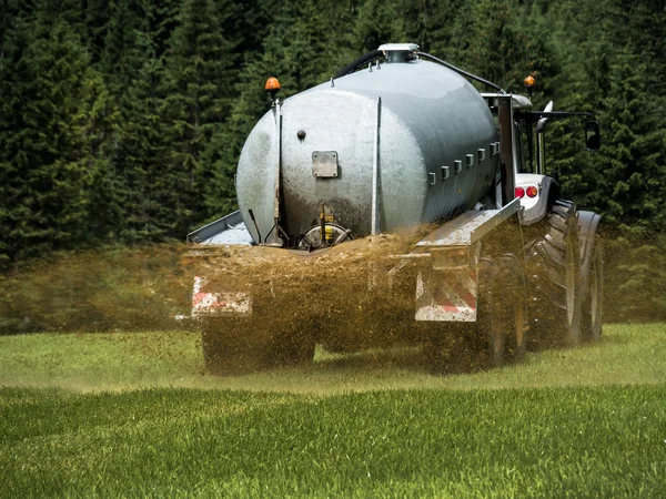 Bauer fertiliza um campo com estrume — Fotografia de Stock