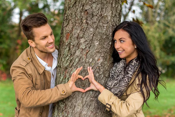 Courting couple behind a tree — Stock Photo, Image