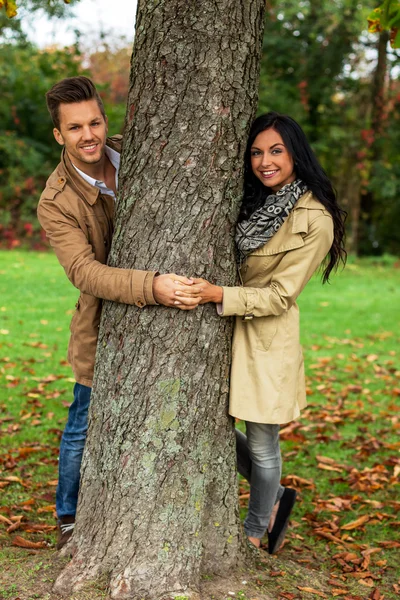 Courtiser couple derrière un arbre — Photo