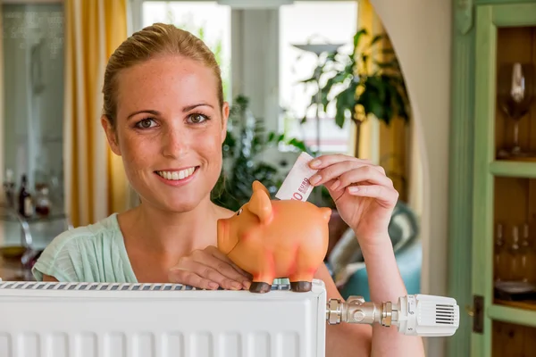 Vrouw met radiator en piggy bank — Stockfoto