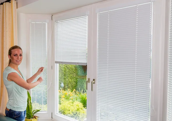 Woman lets down blinds — Stock Photo, Image