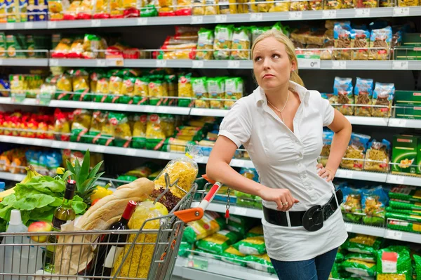 Žena s nákupním vozíkem v supermarket — Stock fotografie