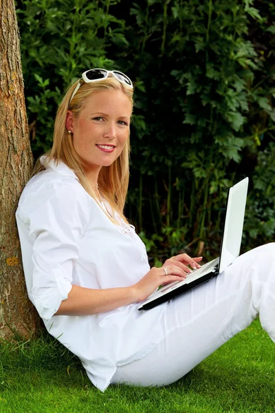 Vrouw met laptopcomputer in de tuin — Stockfoto