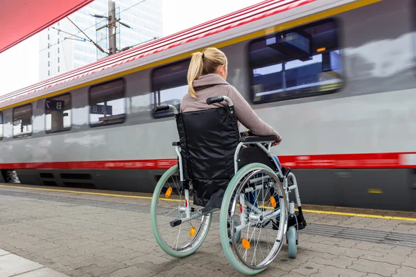 Mujer sentada en una silla de ruedas en una estación de tren — Foto de Stock