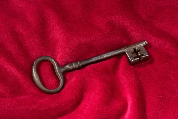 Key on a red velvet cushion — Stock Photo, Image