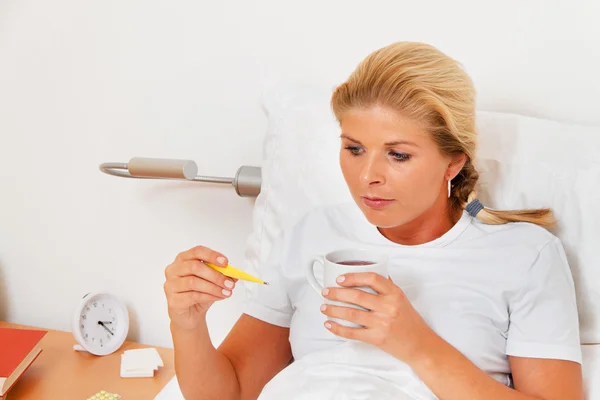 Mujer en cama enferma y tiene un termómetro de fiebre . — Foto de Stock