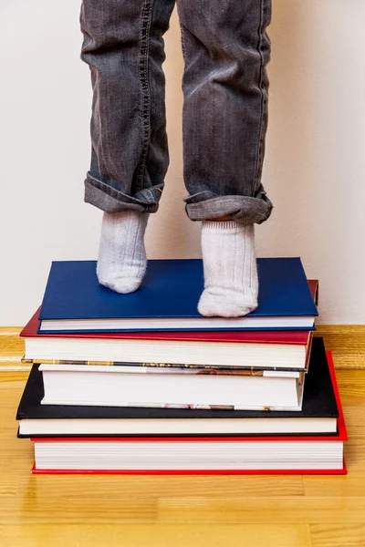 Criança em pé sobre uma pilha de livros — Fotografia de Stock