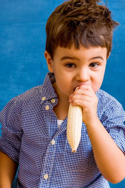 En liten gutt som spiser en banan – stockfoto